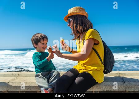 Mamma con suo figlio piccolo che mangia gelato in riva al mare durante le vacanze estive Foto Stock