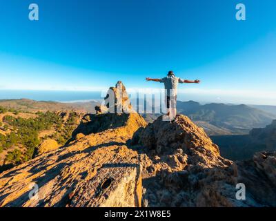 Un turista a braccia aperte sulla cima di Pico de las Nieves a Gran Canaria, Isole Canarie Foto Stock