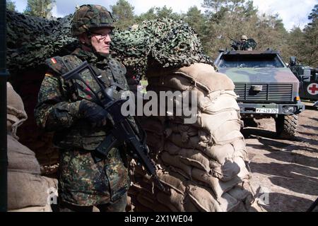 Soldat hinter einem Schutzwall aus Sandsaecken, an einem Checkpoint, Strassensperre, Bundespraesident Frank-Walter STEINMEIER besucht die Uebung National Guardian, Die Panzertruppenschule und die Militaerseelsorge auf dem Truppenuebungsplatz in Munster, 18.04.2024, *** soldato dietro un muro protettivo di sacchi di sabbia, in un posto di sicurezza, in un blocco stradale, il presidente tedesco Frank Walter STEINMEIER visita l'esercitazione del National Guardian, la scuola per le truppe di carri armati e la cappellania militare presso l'area di addestramento delle truppe di Munster, 18 04 2024, Foto Stock