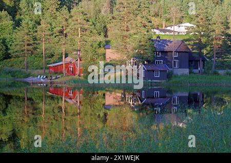 Case e alberi che si riflettono in un lago tranquillo, Idyll, Morgedal, Telemark, Norvegia Foto Stock