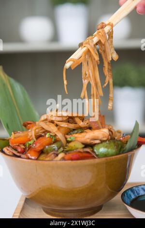 Mescolare il pollo fritto con le verdure in un recipiente su un tavolo di legno Foto Stock