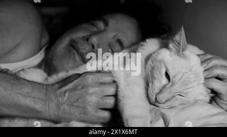 Un uomo addormentato a letto vicino a un gatto. Foto Stock