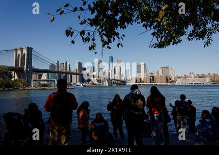 Persone a Pebble Beach a Main Street Park, Brooklyn, guardano i grattacieli di Lower Manhattan dietro East River e il ponte di Brooklyn, New York Foto Stock