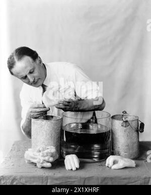 Harry Houdini realizza mani spirituali - 1923 - in questa sequenza di fotografie Houdini ha dimostrato come le mani spiritose apparse alle sedute fossero fatte da esseri meno eterei. In "Un mago tra gli spiriti" Houdini descrisse la frode mediumistica nota come "impronte digitali di uno spirito". Una sagoma della mano di un morto sarebbe stata accuratamente preparata e, durante una seduta con i parenti creduti, le impronte digitali del defunto apparivano su una tromba nera di lampione. Nel suo libro Houdini ha dichiarato quanto segue: "Ci sono due casi registrati in cui le fortune erano in gioco a causa di questo tipo di frode. In uno Foto Stock