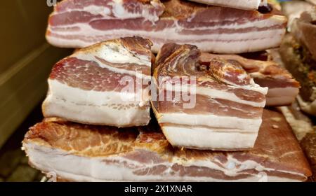 Tagli spessi di pancetta impilati con marmorizzazione visibile di grasso e carne in esposizione, che mostrano la freschezza dei prodotti e l'alta qualità, gruppo di oggetti det Foto Stock