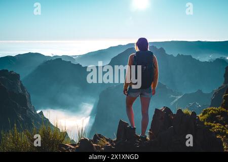 Descrizione: Backpacker toruist sorge sul bordo di una valle profonda e ricoperta di nuvole e gode di una vista panoramica mozzafiato della montagna vulcanica Foto Stock