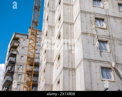 Edificio residenziale a più piani in costruzione, con pareti in cemento esposte e una gru gialla accanto. Industria dello sviluppo abitativo, nuovo vero est Foto Stock