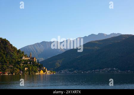Bellissimo Villaggio Morcote con Chucrh sul Lago di Lugano e paesaggio montano con cielo azzurro a Morcote, Ticino, Svizzera. Foto Stock