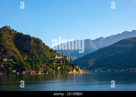 Bellissimo Villaggio Morcote con Chucrh sul Lago di Lugano e paesaggio montano con cielo azzurro a Morcote, Ticino, Svizzera. Foto Stock