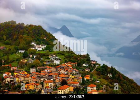 Vista aerea sul paesaggio montano e sul villaggio alpino di Bre con la foresta autunnale e il lago di Lugano in una giornata nuvolosa a Monte Bre, Lugano, Ticino, Svizzera, Foto Stock