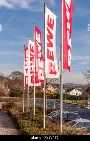 Neuwied, Germania - 29 gennaio 2024: Bandiere in rosso e bianco del negozio di alimentari "REWE" al sole Foto Stock