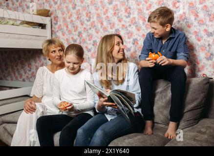 Un gruppo eterogeneo di persone è seduto a stretto contatto sulla sommità di un divano. Sembrano rilassati e impegnati in una conversazione, con vari expre Foto Stock
