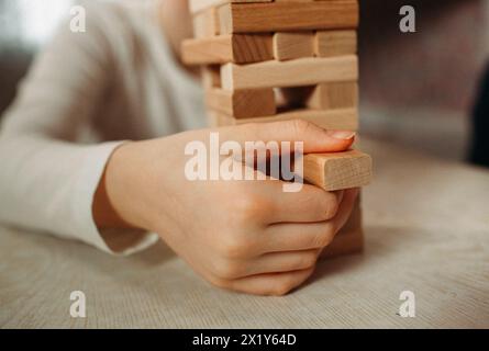 Un bambino giovane impegnato nel gioco, costruisce strutture con un colorato blocco di legno adagiato su un pavimento ricoperto da un morbido tappeto. Foto Stock