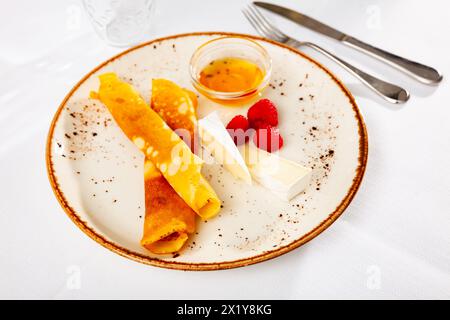 Crepes dolci con brie morbida a fette, lamponi e miele Foto Stock