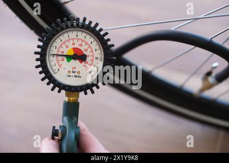 Tenere con la mano un manometro che indica 2,2 bar o 31 psi. Pneumatico per biciclette sfocato sullo sfondo. Contesto: Gonfiaggio degli pneumatici per biciclette, aria, monitoraggio Foto Stock