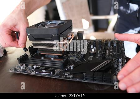 le mani di un giovane maschio installano un refrigeratore con tubi di calore in rame per il processore, altre parti del pc nel case, il concetto di riparazione delle apparecchiature, a. Foto Stock