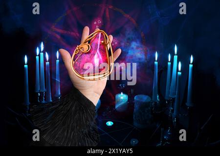 la mano di fortuneteller spiega il significato della pietra magica per raccontare la fortuna per il futuro, nelle stanze buie le candele bruciano nei candelabri, concetto di Foto Stock