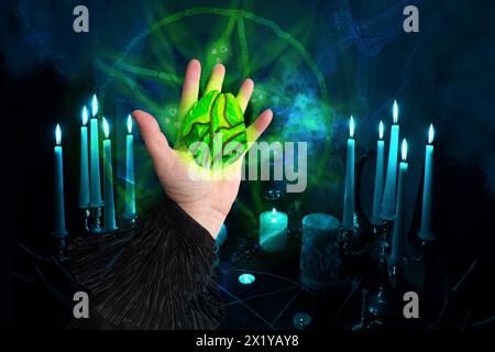 la mano di fortuneteller spiega il significato della pietra magica per raccontare la fortuna per il futuro, nelle stanze buie le candele bruciano nei candelabri, concetto di Foto Stock