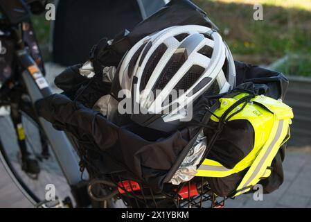 Vista posteriore di una e-bike che mette in risalto il portabagagli per biciclette, che contiene un casco, un giubbotto riflettente, un lucchetto, una copertura antipioggia e un telone. Poll Foto Stock