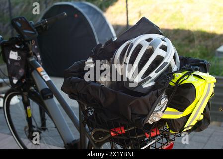 Vista posteriore di una e-bike che mette in risalto il portabagagli per biciclette, che contiene un casco, un giubbotto riflettente, un lucchetto, una copertura antipioggia e un telone. Poll Foto Stock