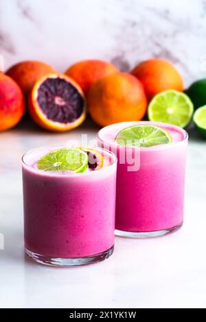 Due Margarita all'arancia di cocco con contorno al lime: Un paio di cocktail di tequila rosa pastello serviti su cubetti di ghiaccio in bicchieri di roccia Foto Stock