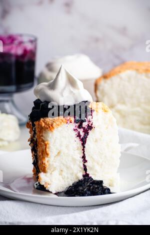 Torta Angel Food con salsa ai mirtilli e panna montata: Fetta di torta di pan di Spagna con marmellata di mirtilli e crema chantilly su un piatto Foto Stock