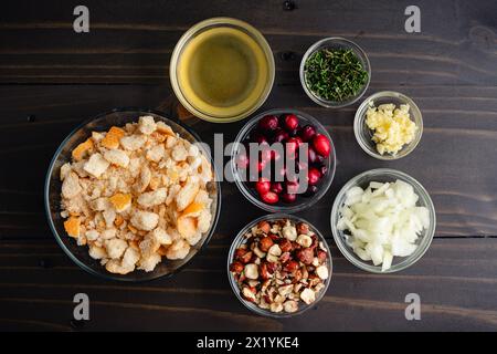 Ingredienti ripieni di nocciole al mirtillo nelle ciotole di preparazione: Pangrattato, mirtilli rossi e altri ingredienti per condire su un tavolo di legno scuro Foto Stock