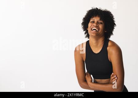 Donna birazziale che ride in studio, indossa abbigliamento sportivo nero, copia spazio Foto Stock