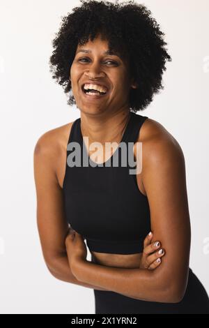 Donna birazziale con capelli ricci che ride in studio, indossando un abbigliamento sportivo nero Foto Stock