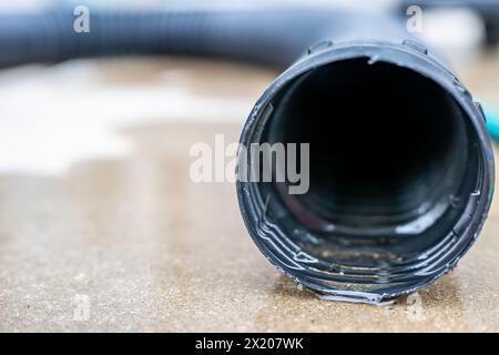 Attenzione selettiva all'apertura anteriore di una pompa di estrazione residenziale che scarica l'acqua dall'estremità di un flessibile flessibile nero Foto Stock