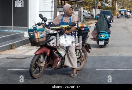 YALA, THAILANDIA, Mar 01 2024, Una donna guida una moto con un carico Foto Stock
