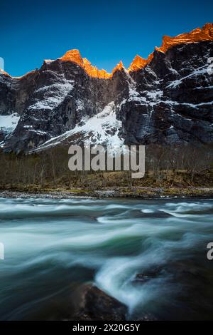 Paesaggio montano con alpenglow mattutino sul Troll Wall e le cime del Trolltindene nella valle di Romsdalen, Rauma kommune, Norvegia. Foto Stock