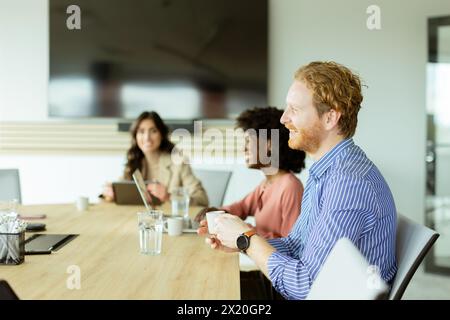 Un gruppo multiculturale di professionisti collabora attorno a un tavolo da conferenza, con dispositivi digitali a portata di mano Foto Stock
