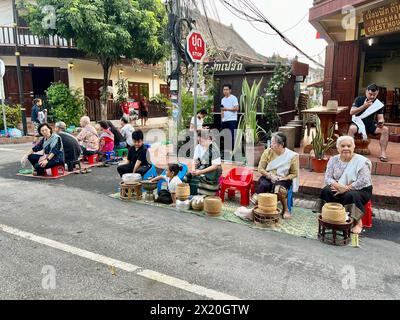 Luang Prabang, Laos. 16 aprile 2024. In una strada nella vecchia città reale di Luang Prabang, i residenti aspettano la mattina presto per la processione dei monaci per dare loro cibo come riso appiccicoso e frutta. L'elemosina è un antico rituale. L'affascinante spettacolo attira ora sempre più turisti da tutto il mondo. Crediti: Carola Frentzen/dpa/Alamy Live News Foto Stock