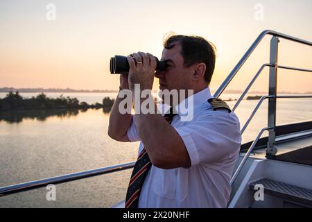 Il capitano Ion Ismana guarda attraverso il binocolo dalla nave da crociera NickoVISION (Nicko Cruises) sul Danubio, vicino a Bratislava, Bratislava, SL Foto Stock