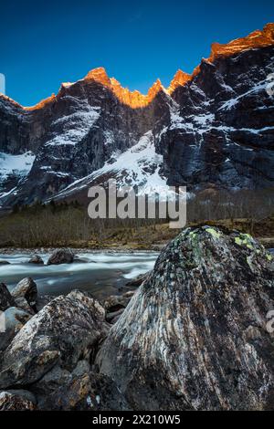 Paesaggio montano con alpenglow mattutino sul Troll Wall e le cime del Trolltindene nella valle di Romsdalen, Rauma kommune, Norvegia. Foto Stock