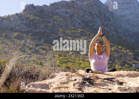 Escursionista birazziale che indossa il rosa pratica yoga su una montagna, copia spazio Foto Stock