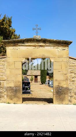 Un arco di pietra con una croce in cima. L'arco è aperto e il cielo è blu. Cancello del cimitero Foto Stock