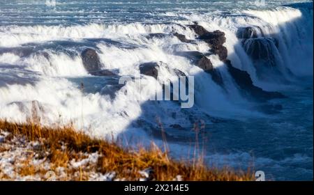 Una cascata con una scogliera rocciosa dietro di essa. L'acqua si schianta e crea un'atmosfera nebbiosa. Il cerchio d'Oro, Islanda. Foto Stock