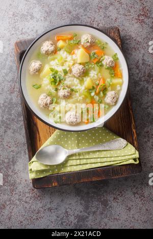 Zuppa di riso con polpette di sedano, carote, cipolle e patate da vicino in un recipiente sul tavolo. Vista dall'alto verticale Foto Stock