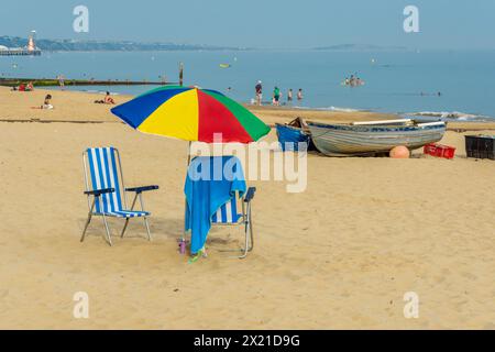 Alum Chine Beach, Bournemouth, Regno Unito - 9 settembre 2023: Sdraio e ombrellone davanti alle barche a remi sulla spiaggia. Foto Stock