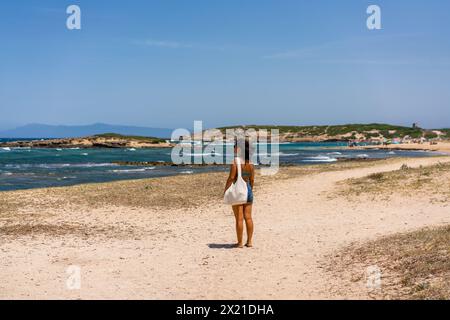 Vista posteriore della donna con costume da bagno su una spiaggia con acqua turchese Foto Stock