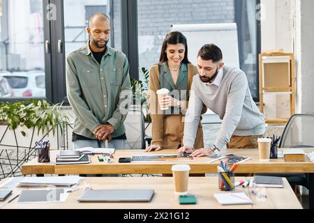 Un gruppo eterogeneo di persone in abbigliamento da lavoro si trova intorno a un tavolo di legno, impegnato in una discussione di progetto. Foto Stock
