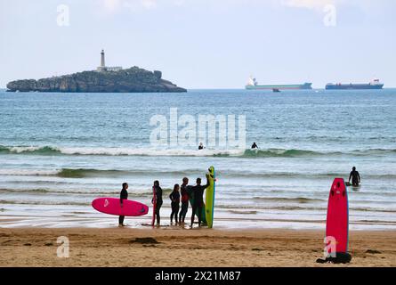 Lezioni di surf di gruppo in un pomeriggio tranquillo con navi da carico ancorate all'orizzonte e spiaggia di Mouro Island Somo Ribamontán al Mar Cantabria Spagna Foto Stock