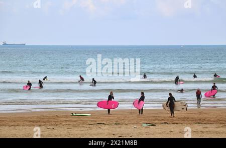 Lezioni di surf di gruppo in un tranquillo pomeriggio di settembre con una nave cargo ancorata all'orizzonte sulla spiaggia di Somo Ribamontán al Mar Cantabria, Spagna Foto Stock