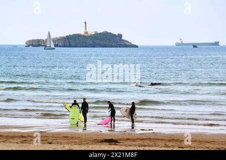 Lezioni di surf di gruppo in un pomeriggio tranquillo con una nave da carico ancorata all'orizzonte e la spiaggia di Mouro Island Somo Ribamontán al Mar Cantabria, Spagna Foto Stock