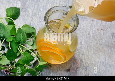 Tè freddo fatto in casa a base di tè alle erbe con succo di mela, succo d'arancia, menta d'acqua, maggiorana selvatica, fase 4: Aggiunta di succo, immagine della serie 4/6 Foto Stock