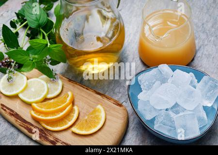 Tè freddo fatto in casa a base di tè alle erbe con succo di mela, succo d'arancia, menta d'acqua, maggiorana selvatica, fase 3: Fette d'arancia, fette di limone e ghiaccio sono adde Foto Stock