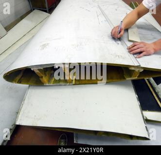 12 aprile 2024, Sassonia, Lipsia: Nel centro tecnico del campus dell’Università di scienze applicate (HTWK), l'assistente alla ricerca Dimitrij Seibert del team guidato dal professore HTWK di costruzione leggera con materiali compositi Robert Böhm prepara una parte di una pala del rotore della turbina eolica di 25 anni smontata per una prova delle sue proprietà meccaniche. Le indagini fanno parte di EuReCOMP, un progetto di ricerca collaborativa finanziato dall'UE che mira a sviluppare metodi sostenibili per il riciclaggio e il riutilizzo di materiali compositi provenienti da componenti dell'energia eolica, tra l'altro. Scienziati Foto Stock
