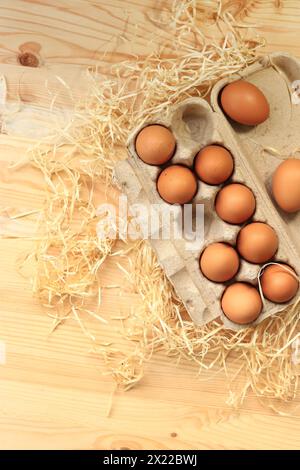 Uova di pollo in una scatola di cartone, vista dall'alto. Uova su fondo di legno. Dieci uova crude fresche. Cuocere le uova di pollo in un vassoio di cartone riciclato su un legnoso Foto Stock